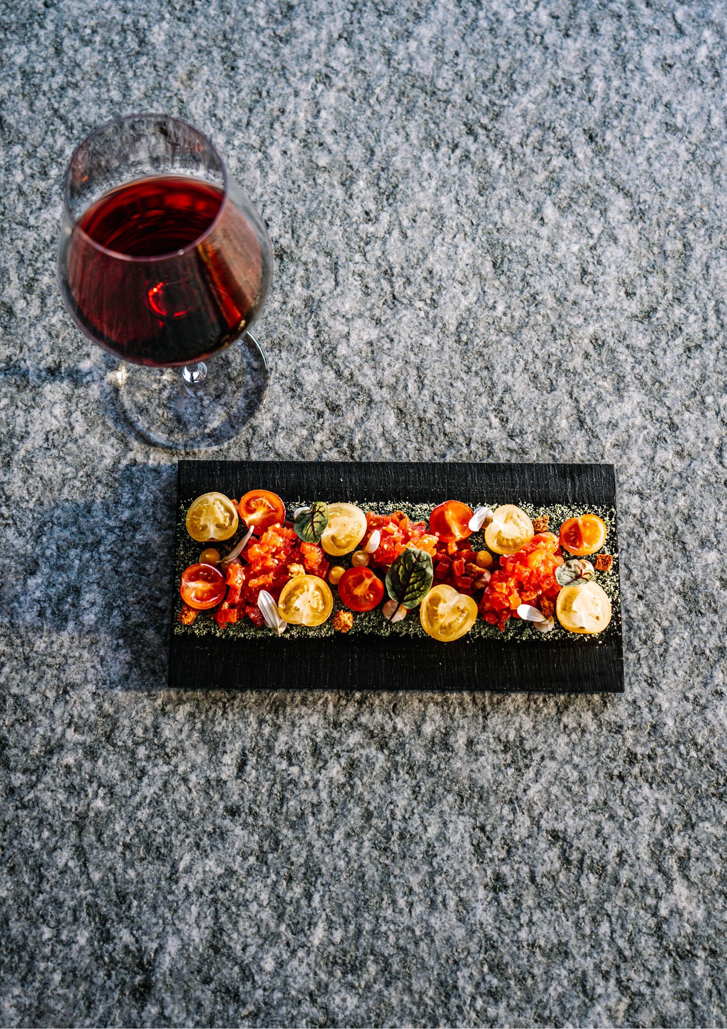 Tartare de tomates anciennes et coulis pimenté sur ardoise noire, accompagné d'un verre de vin rouge
