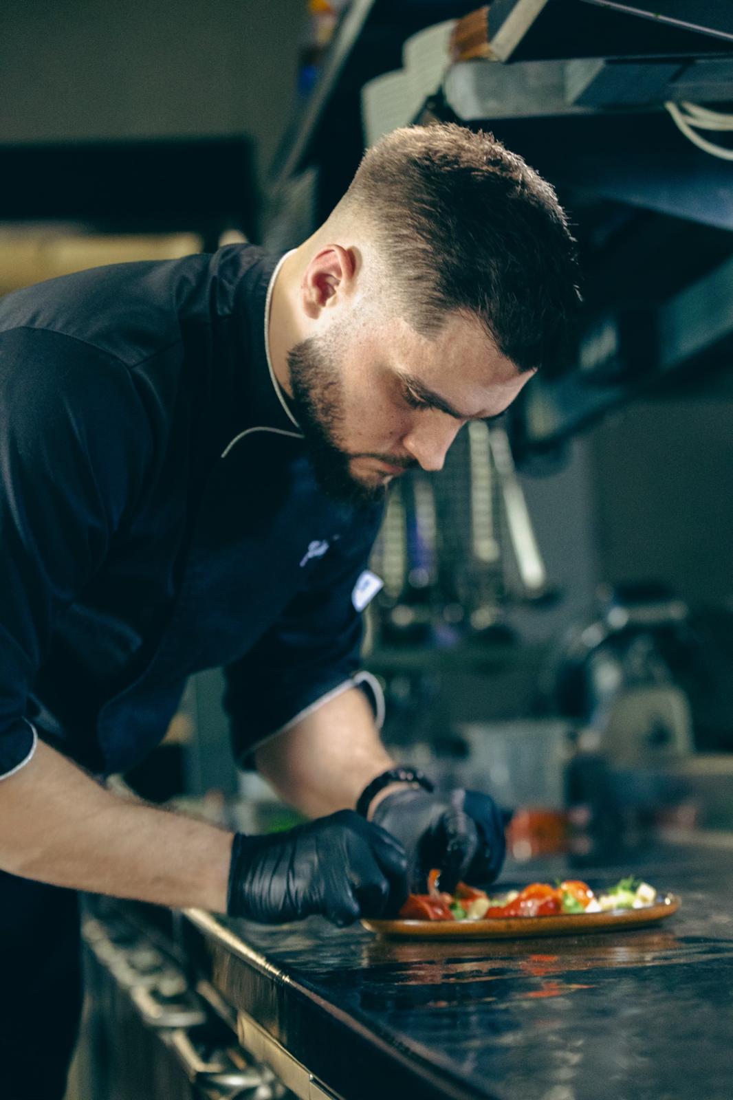 Jérémy Samper en pleine action de dressage en cuisine, vue de profil, mains gantées