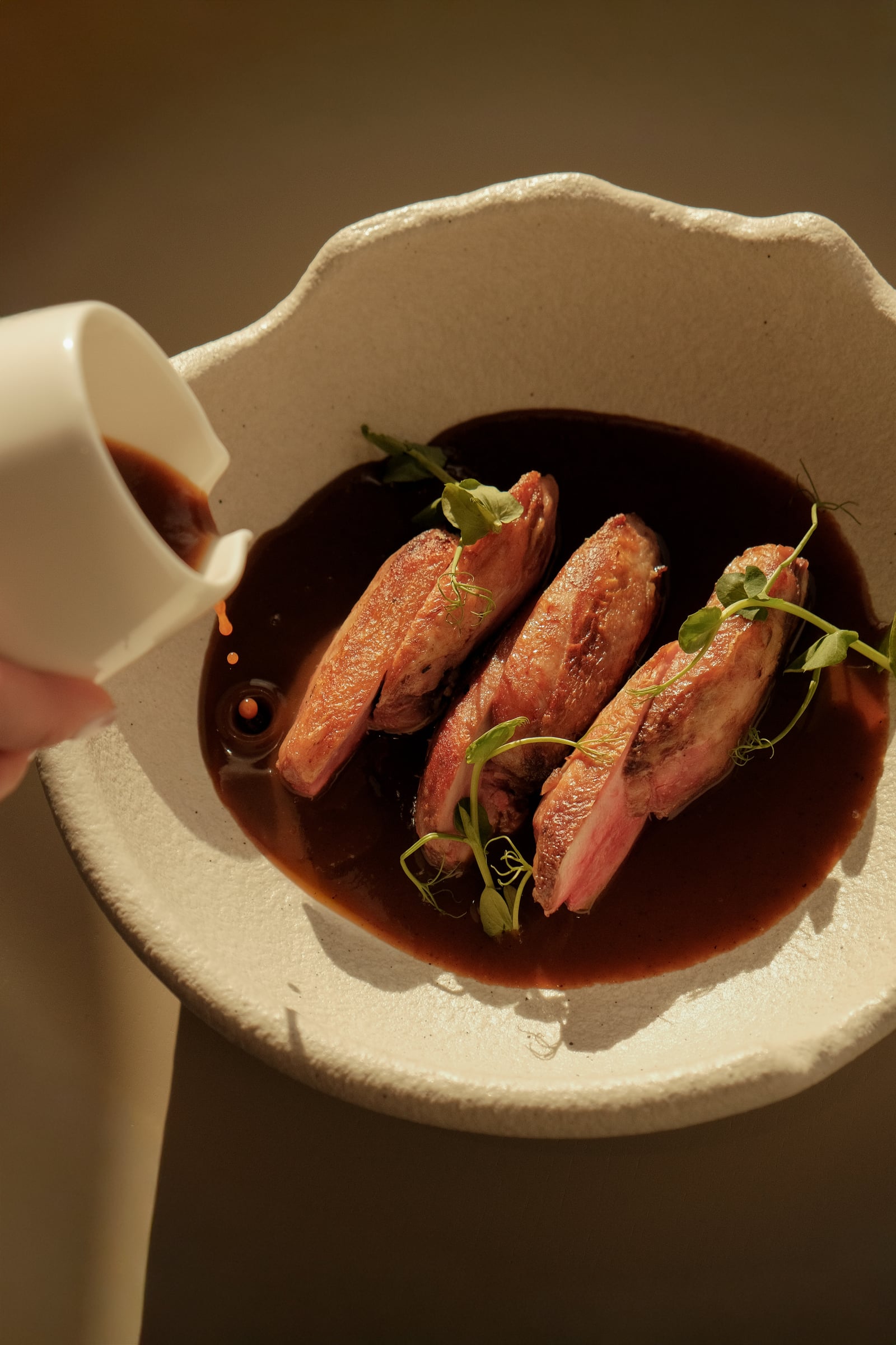 Dressage soigné d'une viande en sauce dans une assiette en céramique